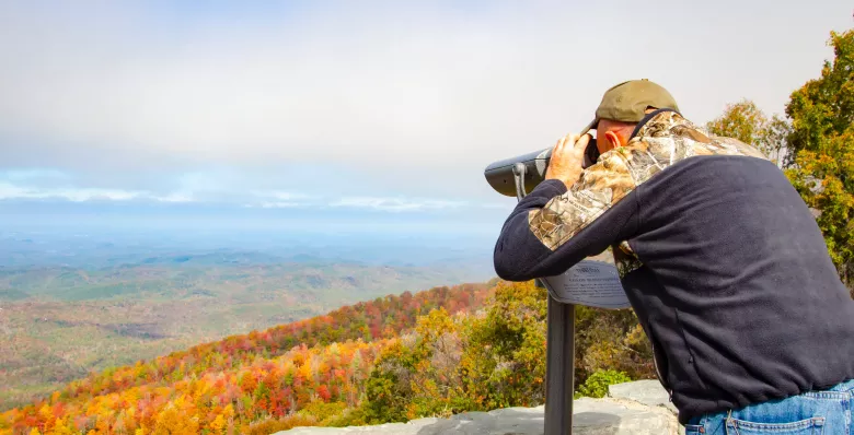 At a scenic overlook at Cherohala Skyway at Turkey Creek. A specialized viewfinder poised on a pedestal beckons those with color visual deficiency to gaze anew at the splendor of a simple magnificent Tennessee landscape. Out on the edge of discovery. Feel the open air on your skin, hear the serenity of nature’s natural sounds. Be at peace. Written about Cherohala Skyway at Turkey Creek Overlook in Tellico Plains, Tennessee.