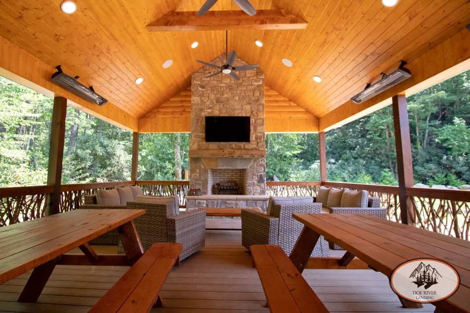 The Water's Edge Pavilion features a covered dining area with tables and seating , fireplace, flat screen TV, and more. Located at Doe River Landing, campground in Roan Mountain, Tennessee.